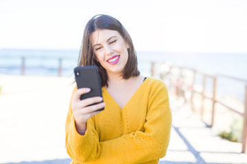 Beautiful young woman smiling positive using smarpthone at the city town