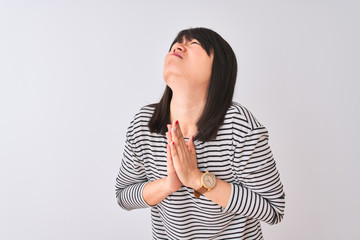Young beautiful chinese woman wearing black striped t-shirt over isolated white background begging...