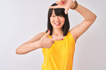Young beautiful chinese woman wearing yellow t-shirt over isolated white background smiling making frame with hands and fingers with happy face. Creativity and photography concept.