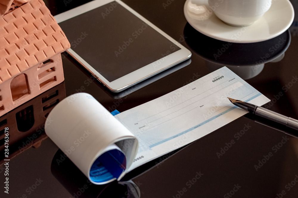 Wall mural checkbook,pen,digital tablet,home model and cup of coffee mockup template isolated on dark backgroun