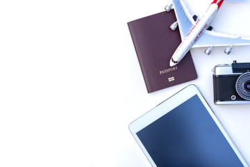 Travel concept. Passport book, camera, technology and airplane isolated white. Top view.