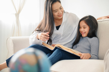 Fototapeta premium mother and child daughter doing homework and reading at home