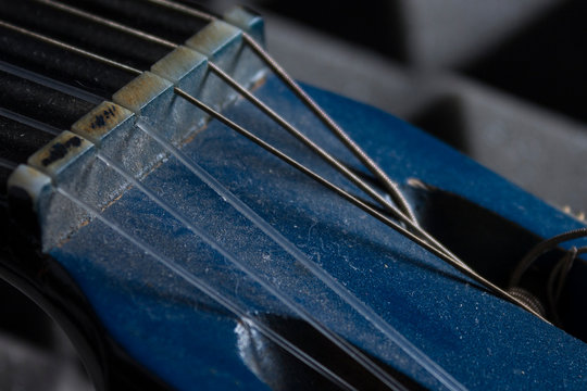 Primer plano de clavijero de guitarra azul con mucho polvo y cuerdas deterioradas para explicar los cuidados de los instrumentos