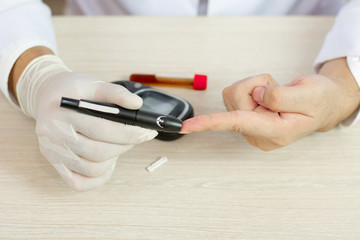 close up of men hands using lancet on finger to check blood sugar level by Glucose meter on chart background.