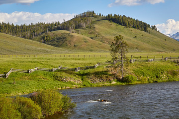 Babbling river running through Sawtooth mountains, green foothills, fields, near Stanley Idaho