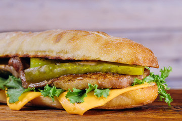 Sandwich with lettuce, slices of pickles, and cheese.