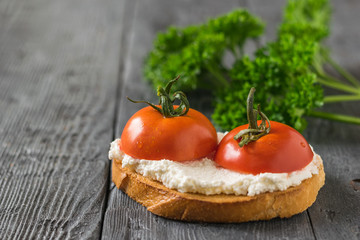 Fresh tomatoes with cottage cheese on a piece of bread on a wooden table.