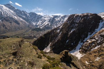 Fototapeta na wymiar View from the mountain to the Georgian villages of Gergeti and Stepantsminda