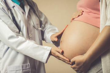 Happy pregnant woman visit gynecologist doctor at hospital or medical clinic for pregnancy consultant. Doctor examine pregnant belly for baby and mother healthcare check up. Gynecology concept.