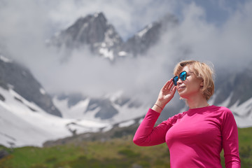 Close up portrait of hiking woman in red at the beautiful mountains background.
