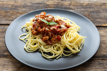 Spaghetti on black plate on wooden background. top view