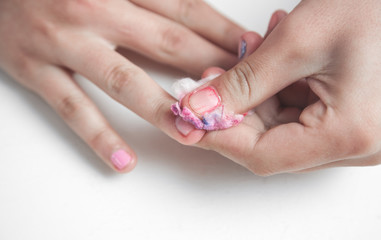 Hands remove the manicure on fingernails.