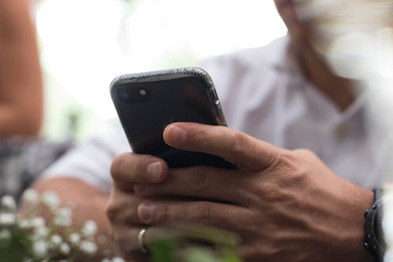 Mano de hombre sosteniendo celular con camisa blanc ay anillo persona desenfadada