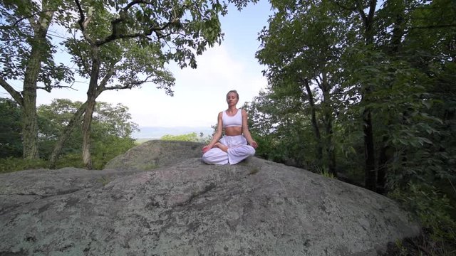 Young woman is practicing yoga at beautiful exotic place on the top of a mountain in slow motion. Yoga and meditation.