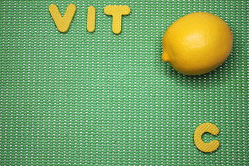 Fresh lemon and VIT C letters on green background