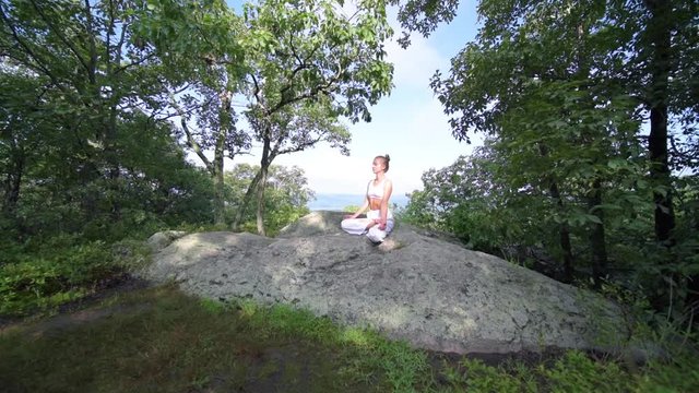 Young woman is practicing yoga at beautiful exotic place on the top of a mountain in slow motion. Yoga and meditation.