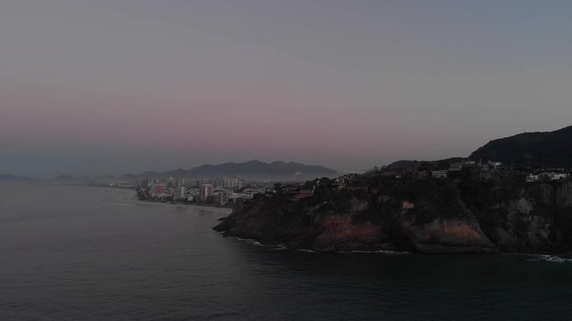 Aerial pan revealing the vast neighbourhood of Barra da Tijuca in Rio de Janeiro with morning mist behind the cliffs of Joatinga beach