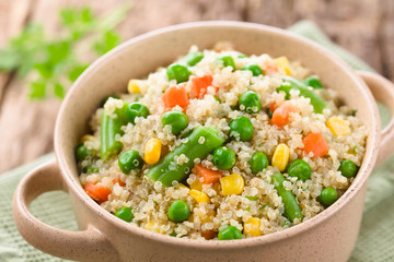 Fresh homemade cooked white quinoa with colorful vegetables (green peas, sweet corn kernels, green beans, carrots) and parsley in bowl (Selective Focus, Focus one third into the dish)