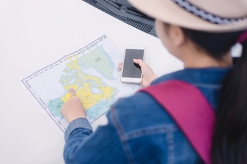 Asian woman using smartphone and map between driving car on road trip