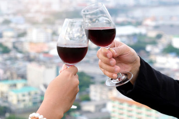 Duration couple romantic dinner time on the terrace at the restaurant, Hand holding red wine and bokeh light , Night city background. Valentine's concept , Dinner Concept.