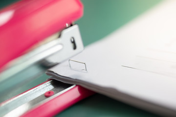 pink stapler does not pierce through many sheets of paper.shallow focus effect.