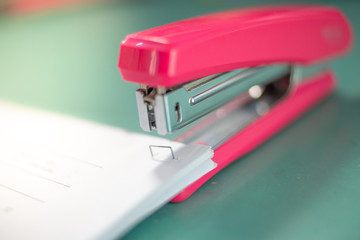 The pink stapler does not pierce through many sheets of paper.shallow focus effect.