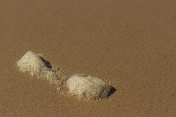 close up of sea foam on smooth golden beach sand