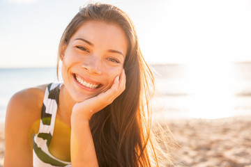 Woman smile happy on beach with healthy glowing skin on sunset sun flare rays summer background....