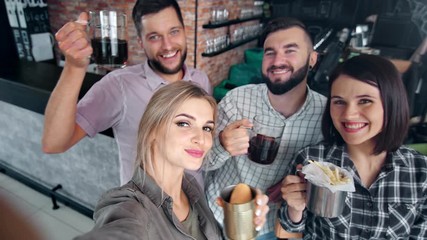 Group of young smiling friend posing with fast food and beer taking selfie POV shot