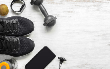 Fit and Healthy lifestyle background concept. sport shoes, smart mobile phone, dumbbell, smart watch, bottle of water on grunge white wood. Top view flat lay style.
