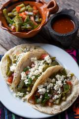 Mexican nopal cactus salad and tacos with cheese on wooden background