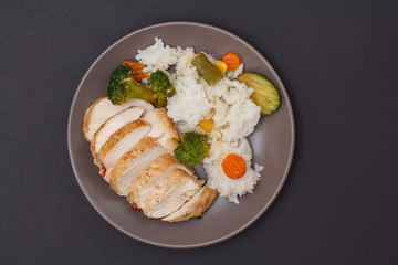 Baked chicken breasts or fillet on plate with rice and vegetables on plate.