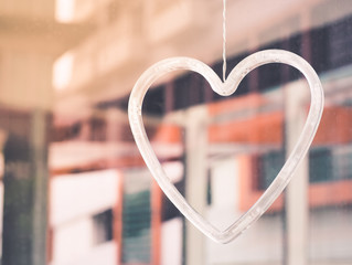 Mobile plastic heart-shaped hanging on a glass plate. Selective focus with space for place your text.