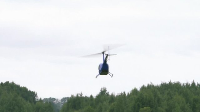 Private helicopter takes off against the gray sky.