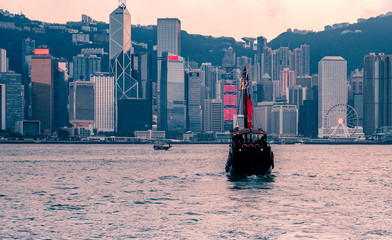 Tourist junk boat in Hong Kong moving from Kowloon harbour at Victoria harbour in the evening