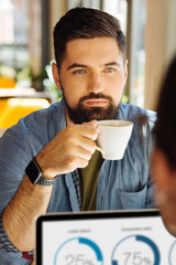 Smart serious bearded man drinking his coffee