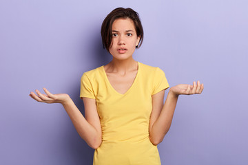 serious, frustrated young girl with raised arms shrugging shoulders isolated over blue background. close up portrait, isolated violet background, studio shot. body language