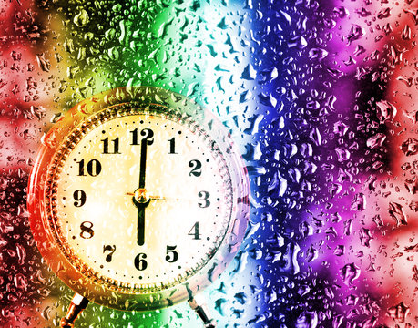 image of a clock outside a window covered with drops of water closeup
