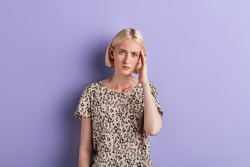 unhappy depressed woman touching her temple ,Beautiful girl suffering from headache. migraine, stress, depression concept, isolated violet background