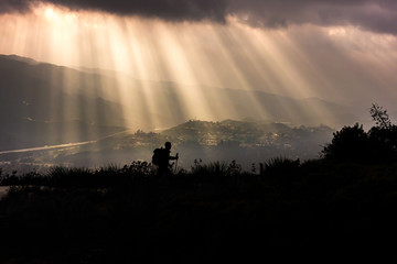 Sunlight Breaks Through the Clouds and Silhouettes Hiker