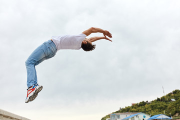 brave guy in white T-shirt and jeans bending his back, stunt performer enjoying his work in the...