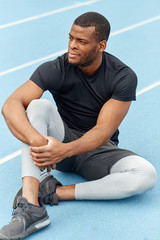 pensive thoughtful strong sportsman having a rest after training outdoors. full length photo. leisure