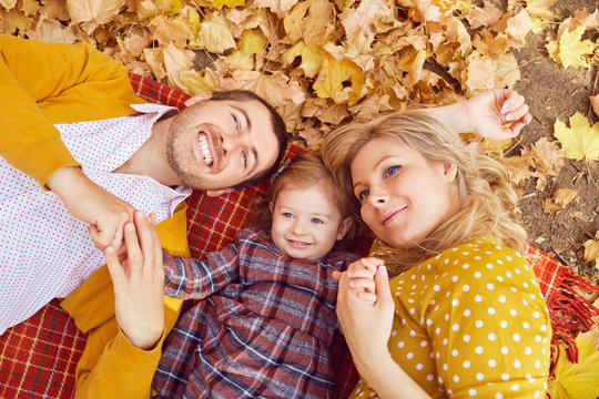 Happy family lying in the park in autumn. - Powered by Adobe