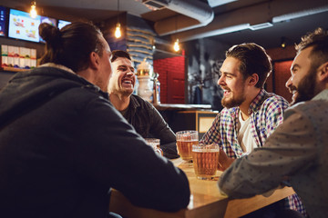 Friends talk, drink beer in a bar.