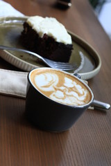 Cappuccino in a cup and brownie on a green plate