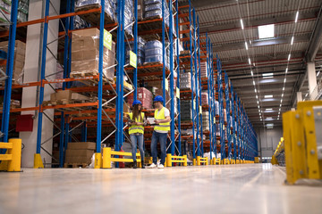 Warehouse workers discussing about logistics and distribution packages to the market. Teamwork in warehouse storage center.