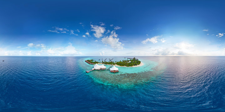 Aerial spherical panorama of tropical paradise beach  on tiny Maldives island. Turquoise ocean and white sand. Small bungalows between coconut palm trees