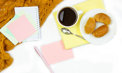 Breakfast in bed. Flat composition with coffee, croissants and a notebook for writing. Lifestyle concept frame. Top view on sheets