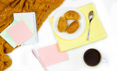 Breakfast in bed. Flat composition with coffee, croissants and a notebook for writing. Lifestyle concept frame. Top view on sheets
