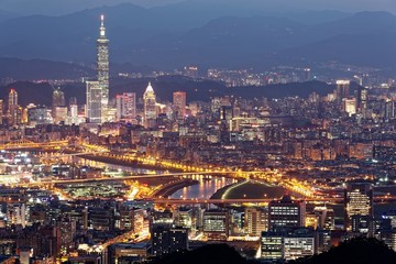 Obraz premium Aerial panorama of Downtown Taipei at night with view of bridges over Keelung River & landmark Tower amid skyscrapers in Xinyi Financial District~ Romantic nightscape of a busy city in a gloomy mood